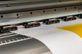 Big professional printer, processing a large scale glossy sheet of yellow paper rolls for color sampling.