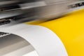 Big professional printer, processing a large scale glossy sheet of yellow paper rolls for color sampling.