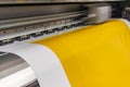 Big professional printer, processing a large scale glossy sheet of yellow paper rolls for color sampling. Royalty Free Stock Photo