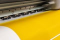 Big professional printer, processing a large scale glossy sheet of yellow paper rolls for color sampling. Royalty Free Stock Photo