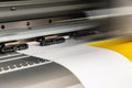 Big professional printer, processing a large scale glossy sheet of yellow paper rolls for color sampling.