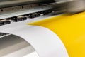 Big professional printer, processing a large scale glossy sheet of yellow paper rolls for color sampling. Royalty Free Stock Photo