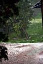 Big rain pours on the street, pours sidewalks and nature. bulks on the water that flows by the stream. trees tilt a powerful wind Royalty Free Stock Photo