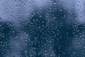 Big rainy droplets on a blue black glass window surface. water drops on dripped background pane in a rainy days in night city wet Royalty Free Stock Photo