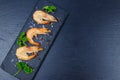 Big raw red prawns with parsley, salt and pepper on slate board on black background. Top view, copy space Royalty Free Stock Photo