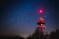 Big red antenna tower lit by red light under a beautiful starry night. Majestic sky above communications tower Royalty Free Stock Photo