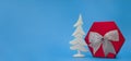 Big red box with silver bow and shiny Christmas tree on blue background. New Year Royalty Free Stock Photo