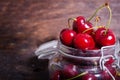 Big red cherries in a glass jar on dark wooden background with copy space. Summer and harvest concept. Cherry macro Royalty Free Stock Photo