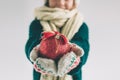 Big red Christmas ball in hands at the girl. The child is dressed in sweater, christmas hat and scarf studio shot. Royalty Free Stock Photo