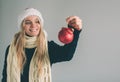 Big red Christmas ball in hands at the women. The girl is dressed in sweater, christmas hat and scarf studio shot Royalty Free Stock Photo