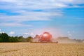 Big red combine working in the field. Agricultural harvester farming wheat.