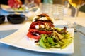 Big red french tomato served with fresh mozzarella cheese, basil pesto and creme balsamico as starter in restaurant in Provence, Royalty Free Stock Photo