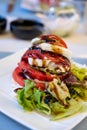 Big red french tomato served with fresh mozzarella cheese, basil pesto and creme balsamico as starter in restaurant in Provence, Royalty Free Stock Photo