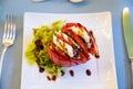 Big red french tomato served with fresh mozzarella cheese, basil pesto and creme balsamico as starter in restaurant in Provence, Royalty Free Stock Photo