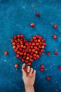 Big red heart made of ripe homegrown cherries on the blue concrete cosmos background. Human hand holding cherries. Summer june Royalty Free Stock Photo