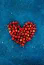 Big red heart made of ripe homegrown cherries on the blue concrete cosmos background. Summer june fruit harvest. Free copy space, Royalty Free Stock Photo