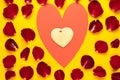 big red heart in it small made of wood in rose petals on yellow background. Copy space. Concept to celebrate valentine's Royalty Free Stock Photo
