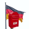 Big red modern metal postbox with note written in German Wahl meaning Vote and standing near German national flag isolated at