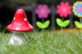 Big red mushroom toy with colorful artificial flowers in background