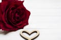 Big red rose and hollow wooden heart on white wooden background. Valentine`s day or Love concept. Royalty Free Stock Photo