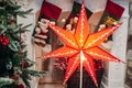 Big red seven pointed Christmas star on the Christmas tree and the fireplace. Royalty Free Stock Photo