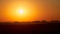 A big red sun in the sunset sky over the roofs of buildings, urban landscape. Evening sky in bright sunlight over the twilight Royalty Free Stock Photo