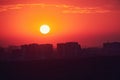 A big red sun in the sunset sky over the roofs of buildings, urban landscape. Evening sky in bright sunlight over the twilight Royalty Free Stock Photo