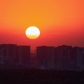 A big red sun in the sunset sky over the roofs of buildings, urban landscape. Evening sky in bright sunlight over the twilight Royalty Free Stock Photo