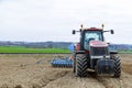 A big red tractor with sowing equipment stands on a field near the railway. Modern technology. Royalty Free Stock Photo