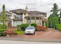 Big residential house with a car parked on pawed drvieway in front