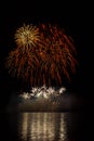 Big and rich orange and yellow stars with crackling effect from fireworks over Brno`s Dam with lake reflection Royalty Free Stock Photo