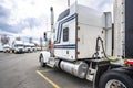 Big rig American bonnet classic white semi truck with extended cab for truck driver comfort standing on the truck stop parking lot Royalty Free Stock Photo