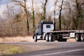 Big rig black semi truck with flat bed semi trailer running on w Royalty Free Stock Photo