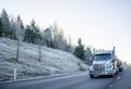 Big rig American semi truck with tank semi trailer transporting liquid cargo on the winter road with frost on the hill Royalty Free Stock Photo