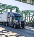 Big rig black stylish diesel semi truck transporting cargo in refrigerator semi trailer running on the arched truss Interstate Royalty Free Stock Photo