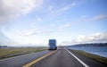 Big rig blue day cab semi truck transporting commercial cargo in dry van semi trailer running on the road in front of another Royalty Free Stock Photo