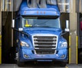 Big rig blue semi truck loading commercial cargo in warehouse dock Royalty Free Stock Photo