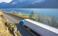 Big rig blue semi truck with refrigerated semi trailer transporting goods running on the road along railroad in Columbia Gorge Royalty Free Stock Photo