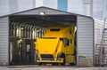 Big rig bright yellow semi truck with open hood washes in a trucks car wash in an industrial zone Royalty Free Stock Photo