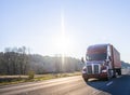 Big rig brown semi truck transporting container moving on the highway at sunshine day Royalty Free Stock Photo