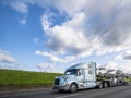 Big rig car hauler semi truck transporting cars on the special semi trailer driving on the flat road with green hill Royalty Free Stock Photo