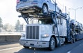 Big rig car hauler semi truck transporting cars on two levels semi trailer driving on winter frosty road