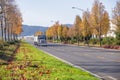 Big rig classic black semi truck with bulk semi trailer moving on the road with autumn yellow trees