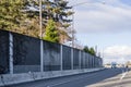 Big rig commercial semi truck turning on the entrance to highway running along the concrete fence on the road side Royalty Free Stock Photo