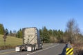 Big rig diesel industrial grade semi truck tractor running without semi trailer on the road with trees Royalty Free Stock Photo