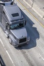 Big rig gray bonnet semi truck transporting goods in refrigerated semi trailer running on multiline highway Royalty Free Stock Photo