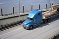 Big rig semi truck with flat bed semi trailer transporting commercial cargo on elevated road Royalty Free Stock Photo