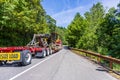 Big rig powerful semi truck transporting oversized excavator on step down semi trailer with oversize load sign driving on the Royalty Free Stock Photo