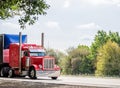 Classic red big rig semi truck with framed covered semi trailer driving on the road to point of delivery Royalty Free Stock Photo