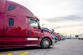 Big rig red powerful semi truck standing in row with another semi truck tractors with semi trailers on truck stop parking lot Royalty Free Stock Photo